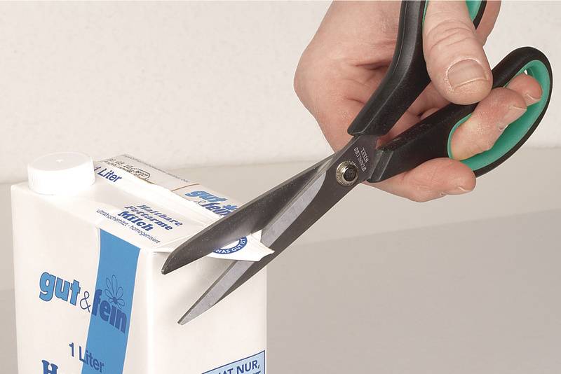 Eine Hand schneidet mit einer Schere eine Ecke eines Tetrapaks auf, um den Inhalt zu öffnen.