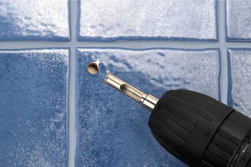 Nahaufnahme eines Bohrers, der ein Loch in eine blaue Fliese bohrt, um handwerkliche Tätigkeiten darzustellen.