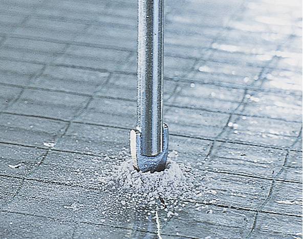 Nahaufnahme eines Bohrers, der in einen gefliesten Boden bohrt, erzeugt Staub und zeigt konkrete Tiefeeindringen.