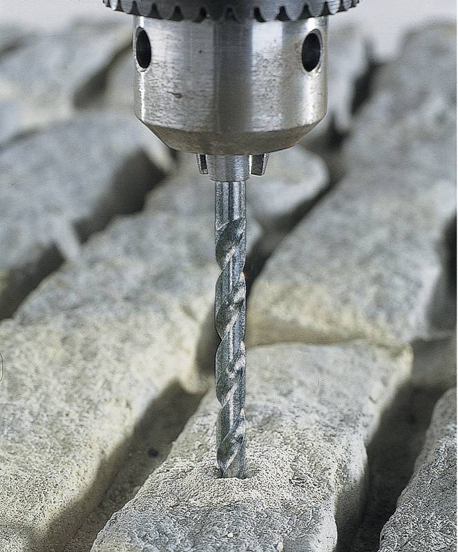 Bohrmaschine mit Metallbohrer, der in einen grauen Stein bohrt. Grobe Oberfläche und staubige Textur sind sichtbar.
