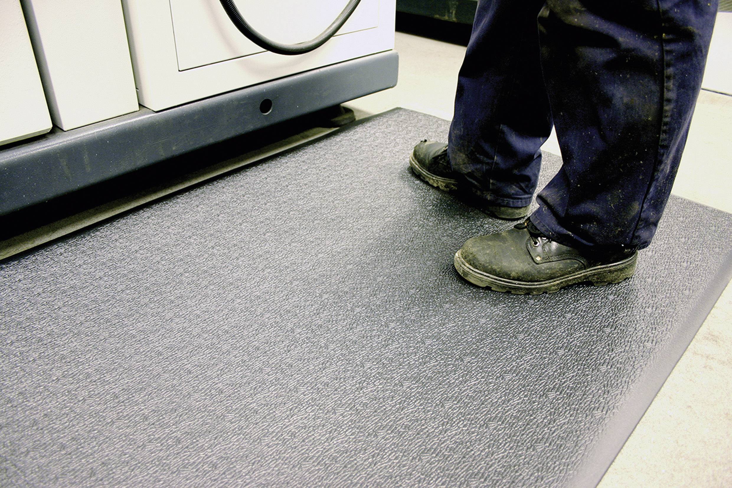 Eine Person steht auf einer rutschfesten Matte vor einer Waschmaschine. Die Matte bietet Stabilität und Sicherheit auf glattem Boden.