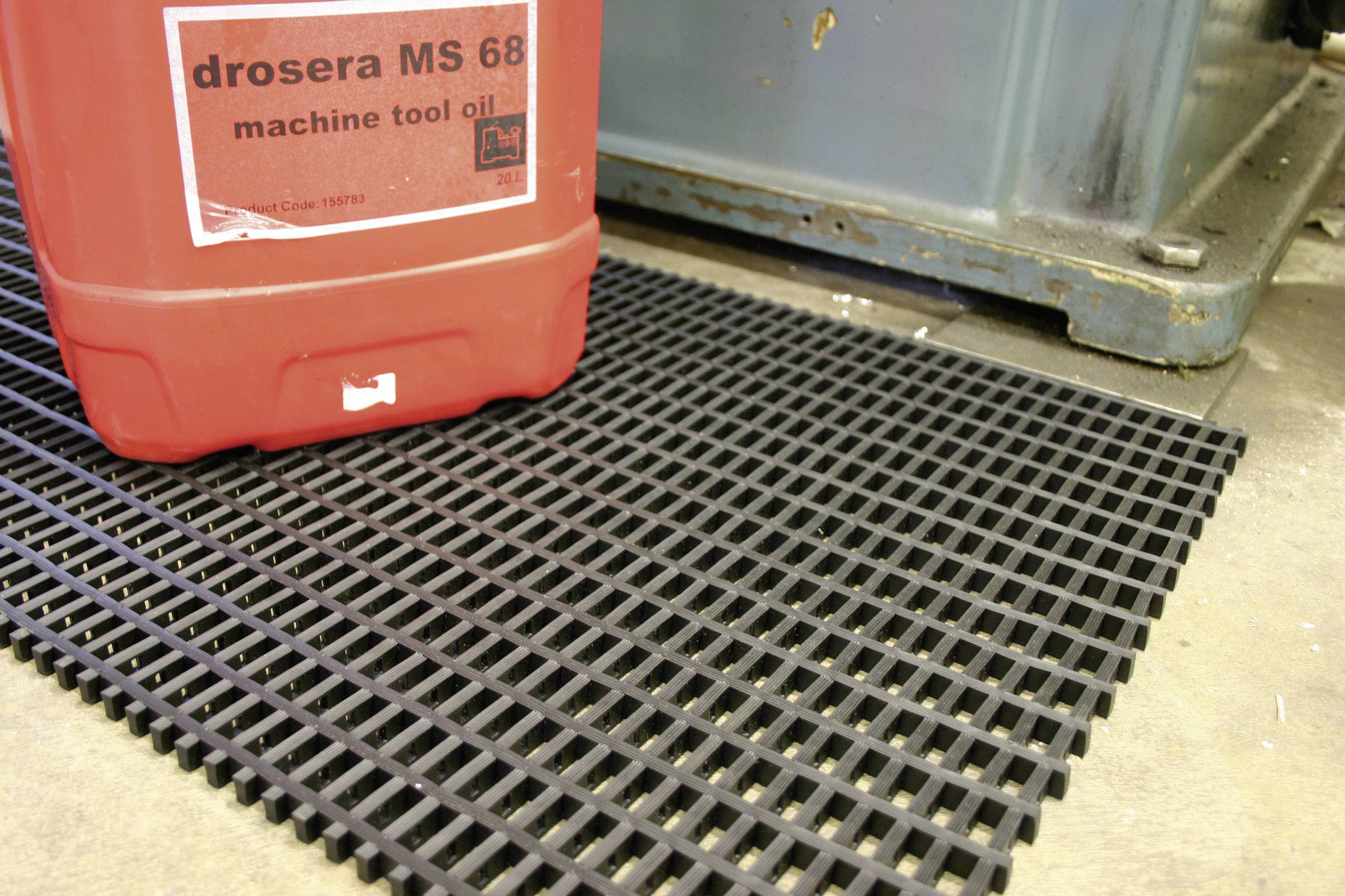 Rote Ölkanne mit der Aufschrift 'drosera MS 68 machine tool oil' steht auf schwarzer Kunststoffmatte neben metallischem Objekt.