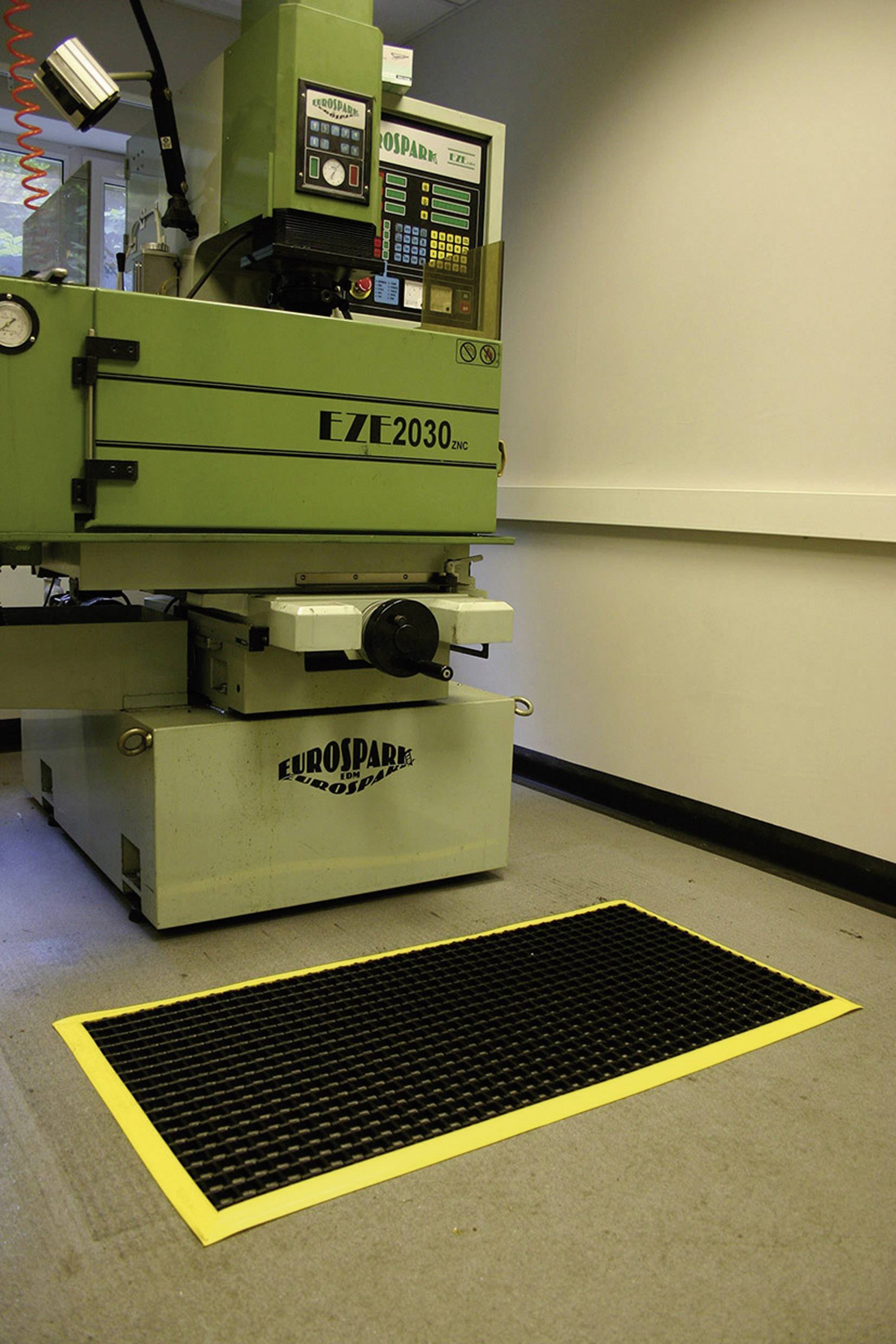 Grüne CNC-Maschine in Werkstatt mit Sicherheitsmatte davor auf dem Boden, umgeben von neutralem Raum.