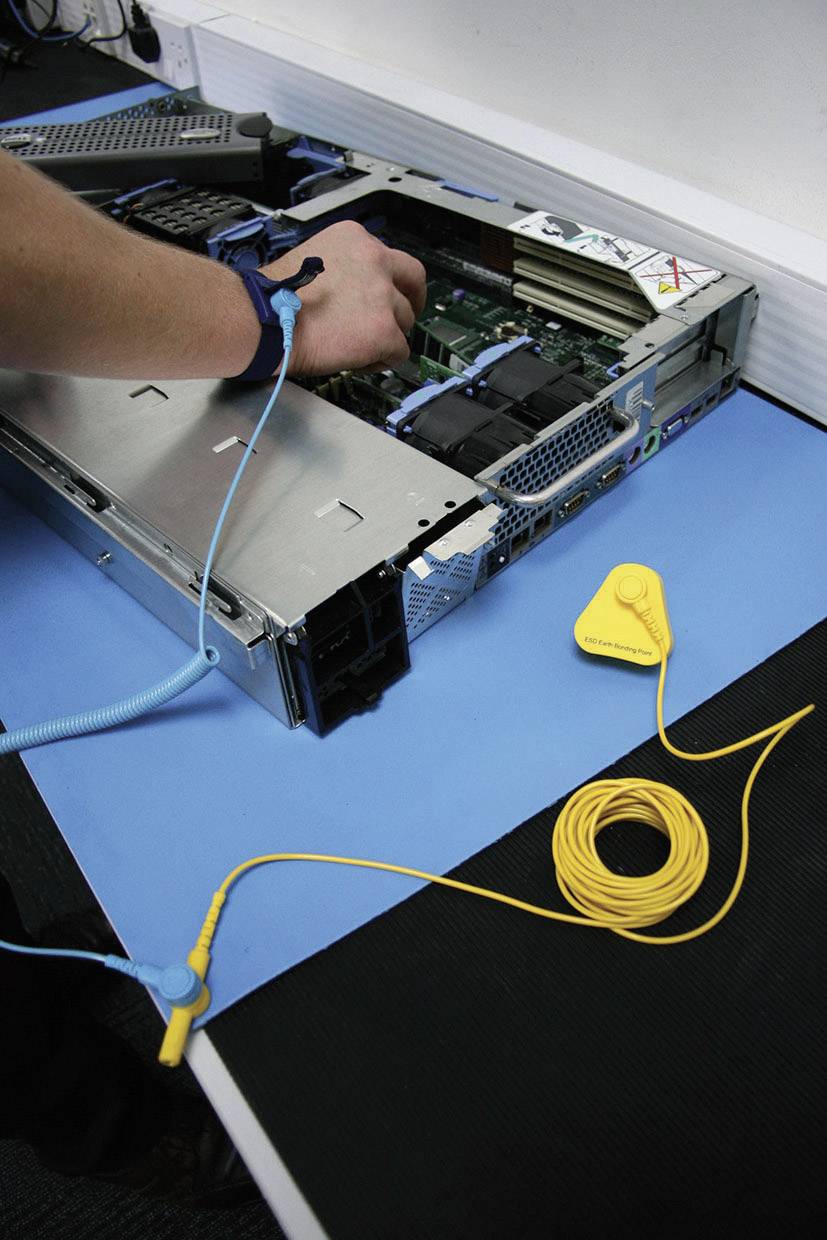Eine Person arbeitet an einem offenen Servergehäuse auf einem Tisch. Sie trägt ein antistatisches Armband, um statische Elektrizität zu vermeiden.