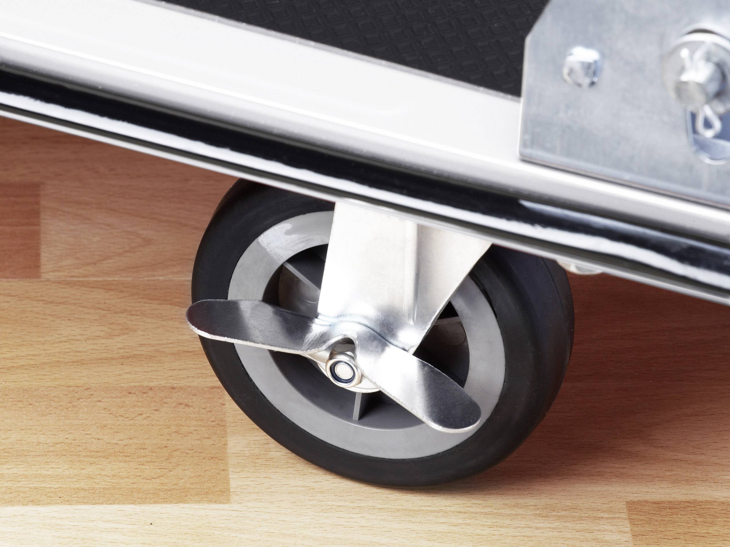 Nahaufnahme eines Flugzeug-Rollkoffers mit einer propellerförmigen Radkappe auf einem Holzboden.