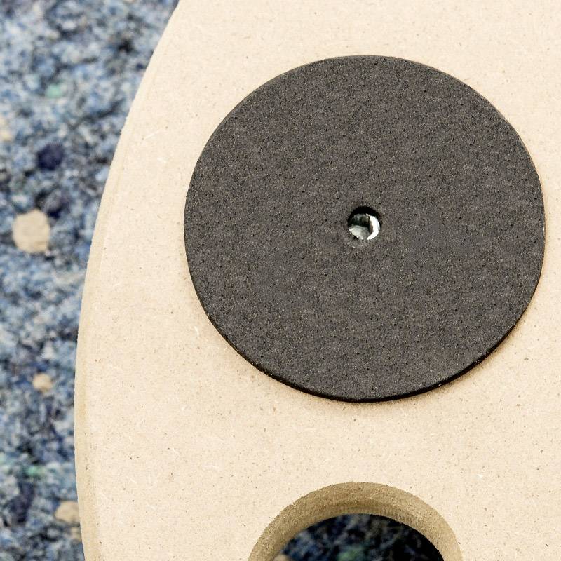 Nahaufnahme eines Akustikgitarren-Schalllochs mit einer schwarzen Feedbackschutzabdeckung auf einem gemusterten Teppich.