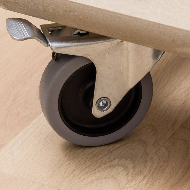 Nahaufnahme eines Möbelrads mit Bremse auf einem Holzboden.