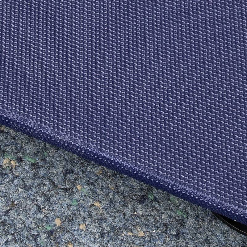 Blauer, strukturierter Teppichrand auf einem grünblauen Boden, der leicht abgenutzt wirkt.