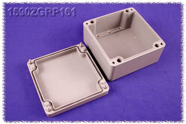 '1590ZGRP161' graue Kunststoff-Verbindungsdose, rechteckig, offene Abdeckung daneben, auf lila Hintergrund.