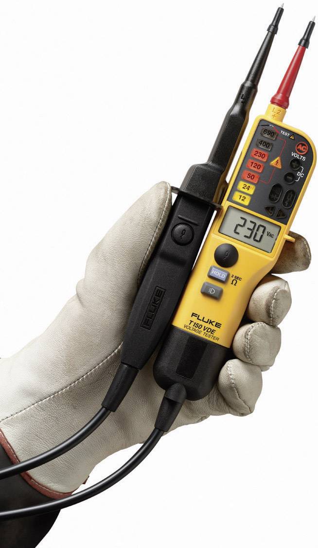 Eine behandschuhte Hand hält ein gelbes Spannungsmessgerät mit einer Anzeige von 230 Volt, umgeben von mehreren farbigen Knöpfen und Skalen.