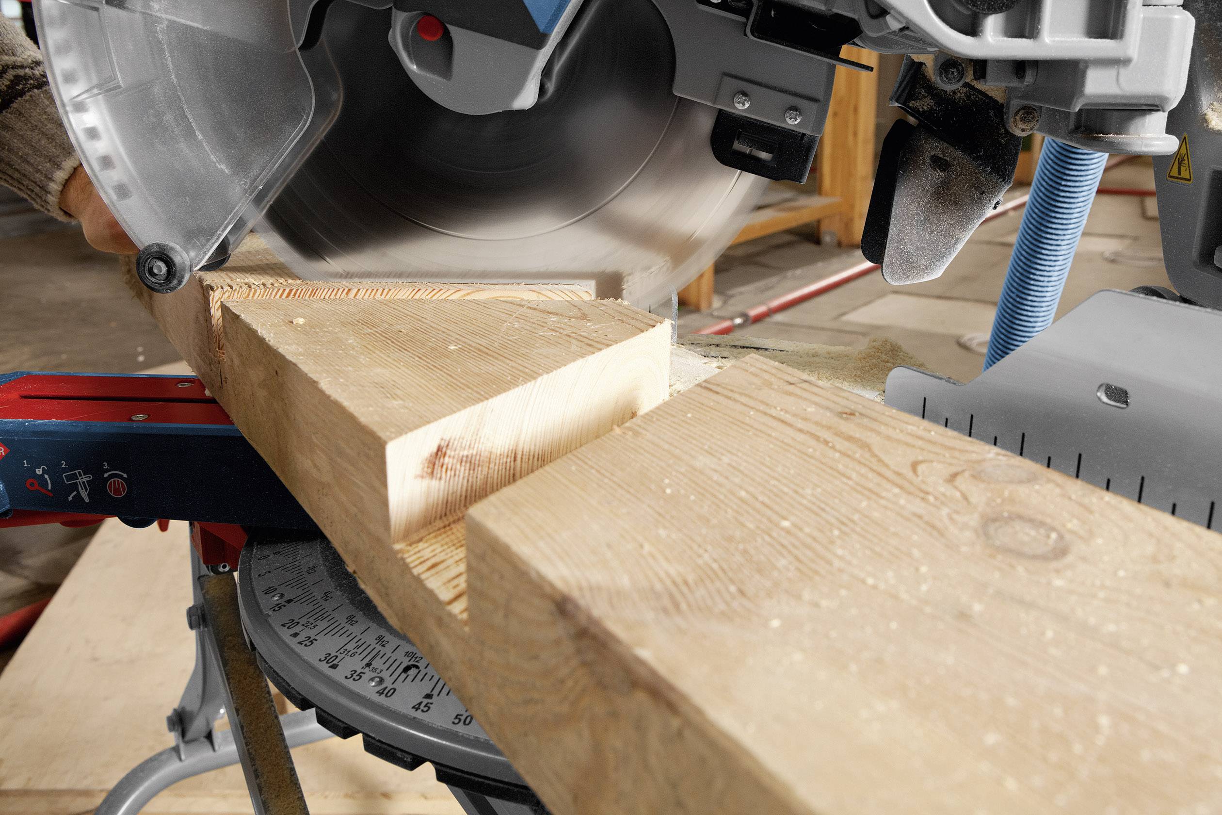 Eine elektrische Kreissäge schneidet ein Holzbrett. Die Säge ist in Bewegung, Sägespäne fliegen. Eine Werkstatt ist im Hintergrund sichtbar.