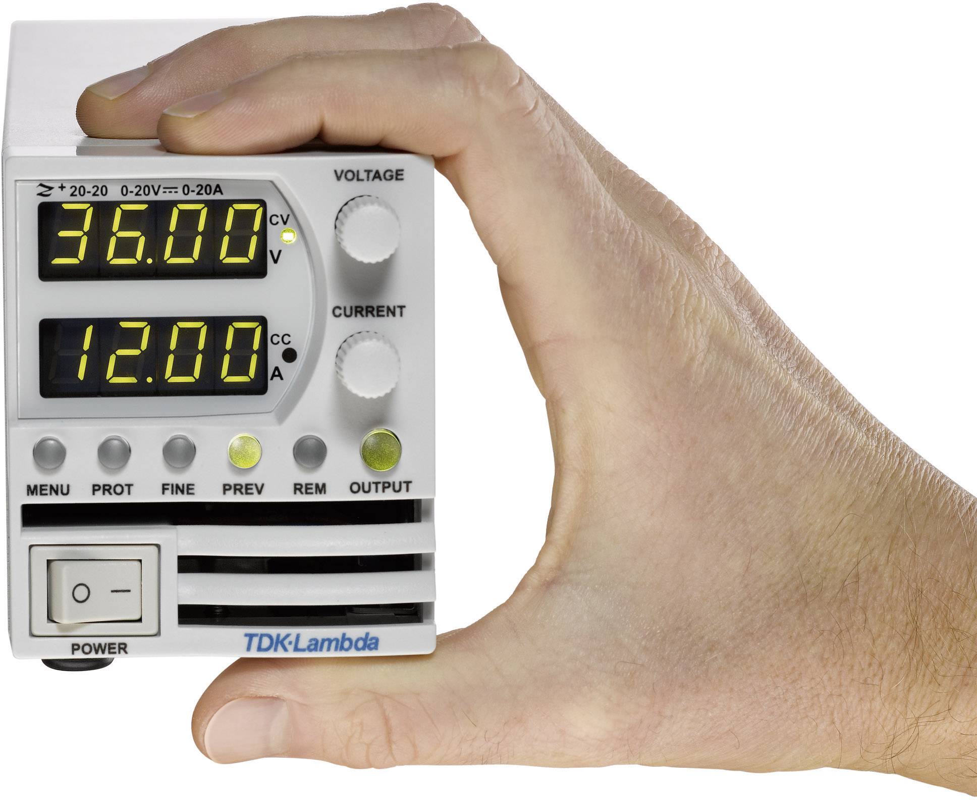 Hand hält ein elektronisches Gerät mit digitaler Anzeige. Oben steht '36,00' Volt, unten '12,00' Ampere. Markenname 'TDK-Lambda' sichtbar.