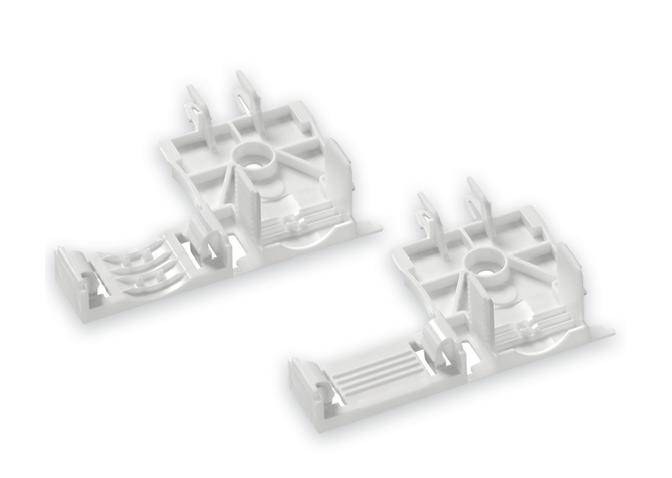 Weiße Kunststoffteile mit komplexen Formen, bestehend aus mehreren Ebenen und Aussparungen, möglicherweise Bauteile für technische Geräte.