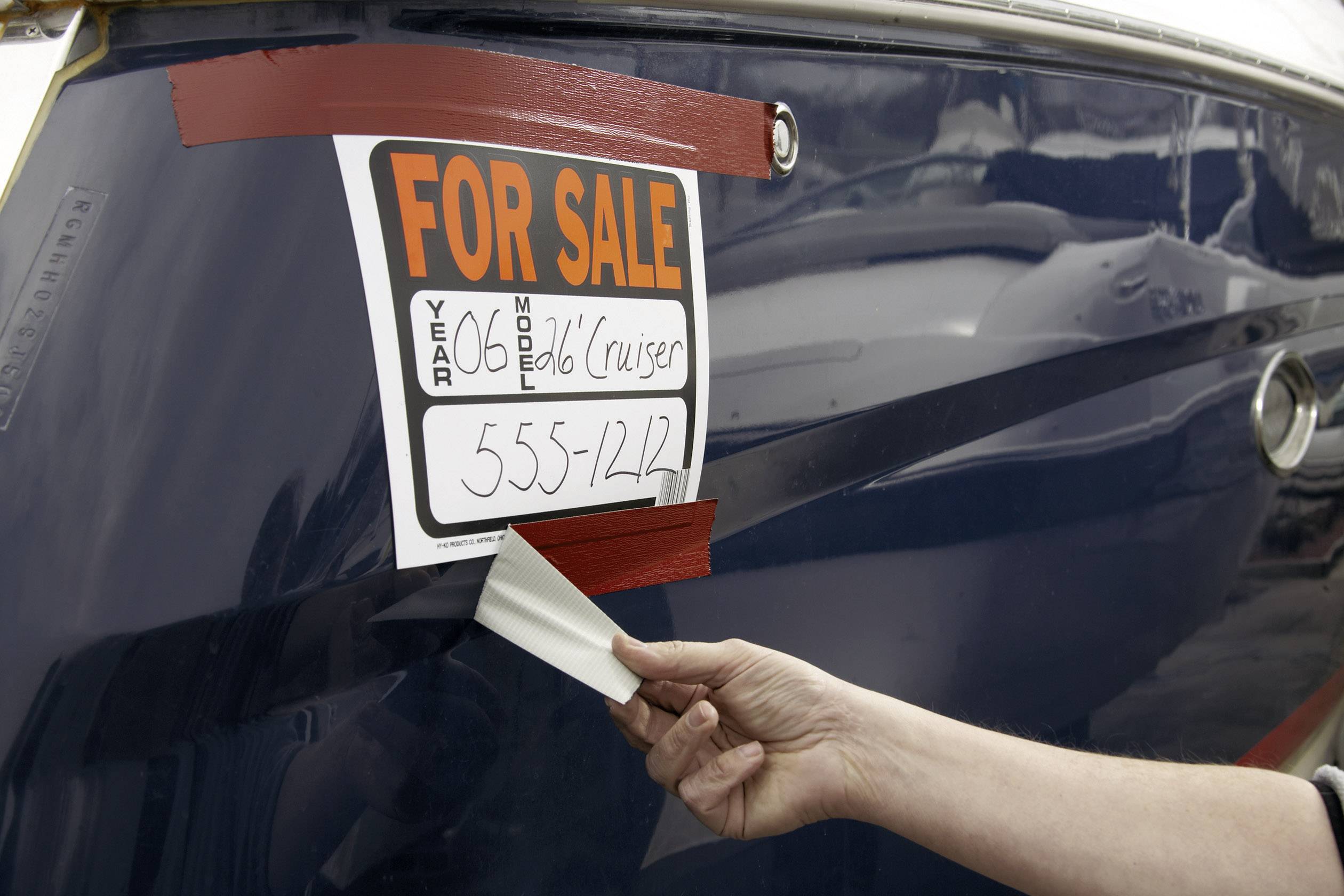 Boot zum Verkauf mit Schild '60er Modell Cruiser, 555-1242'. Eine Hand entfernt alten Aufkleber.