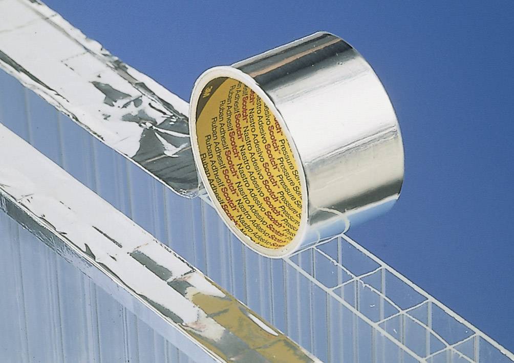 Eine Rolle silbernes Klebeband liegt teilweise abgewickelt auf einer transparenten, strukturierten Oberfläche mit blauer Rückwand.