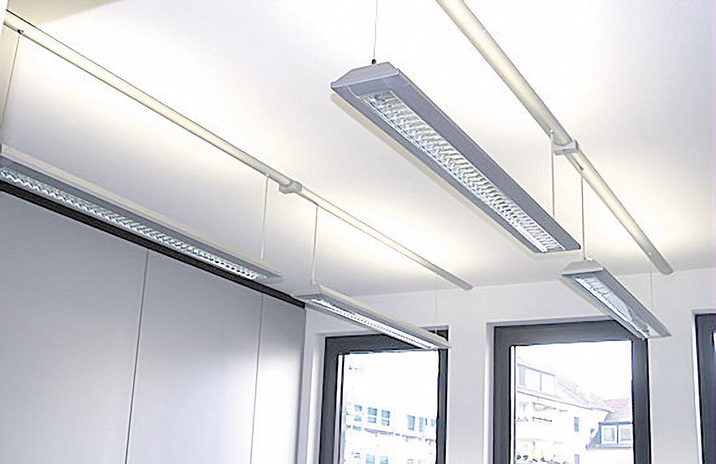 Beleuchtetes Büro mit modernen, weißen Pendelleuchten an der Decke und großen Fenstern, die viel Tageslicht hereinlassen.