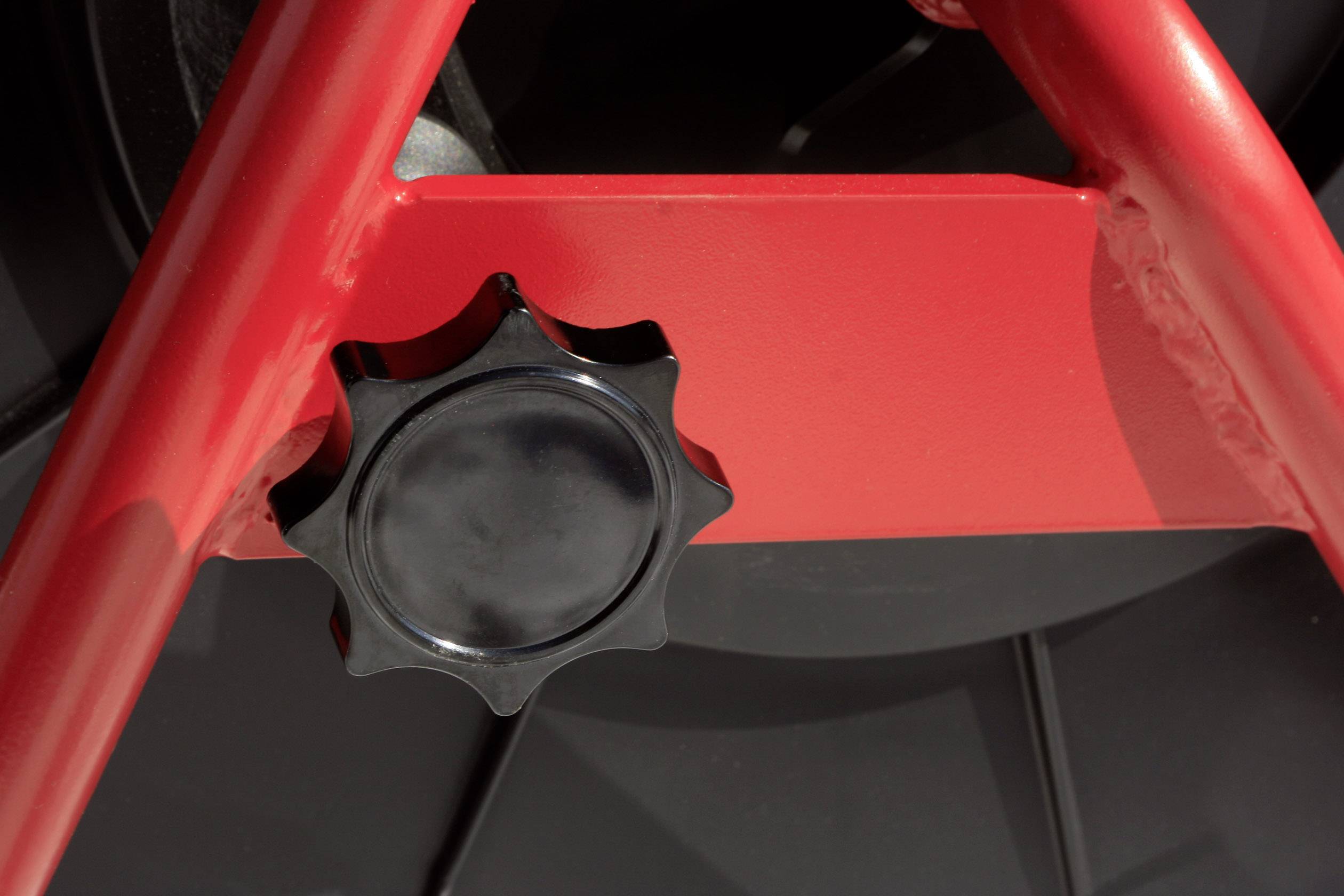 Roter Rahmen mit schwarzem Drehknopf, vermutlich an einem mechanischen Gerät, nah aufgenommen.