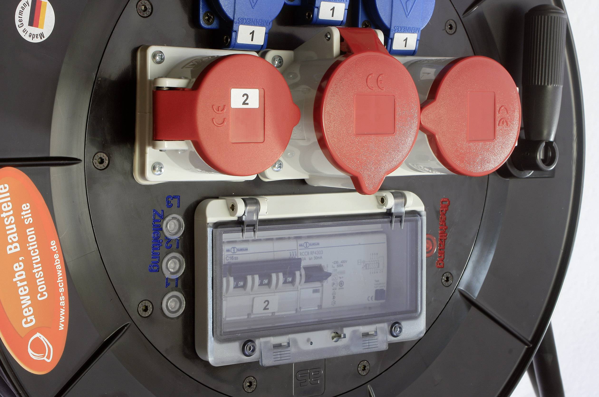 Stromverteiler mit roten und blauen Steckdosen und Schaltern. Auf einem Etikett steht 'Gewerbe, Baustelle, Construction Site'.