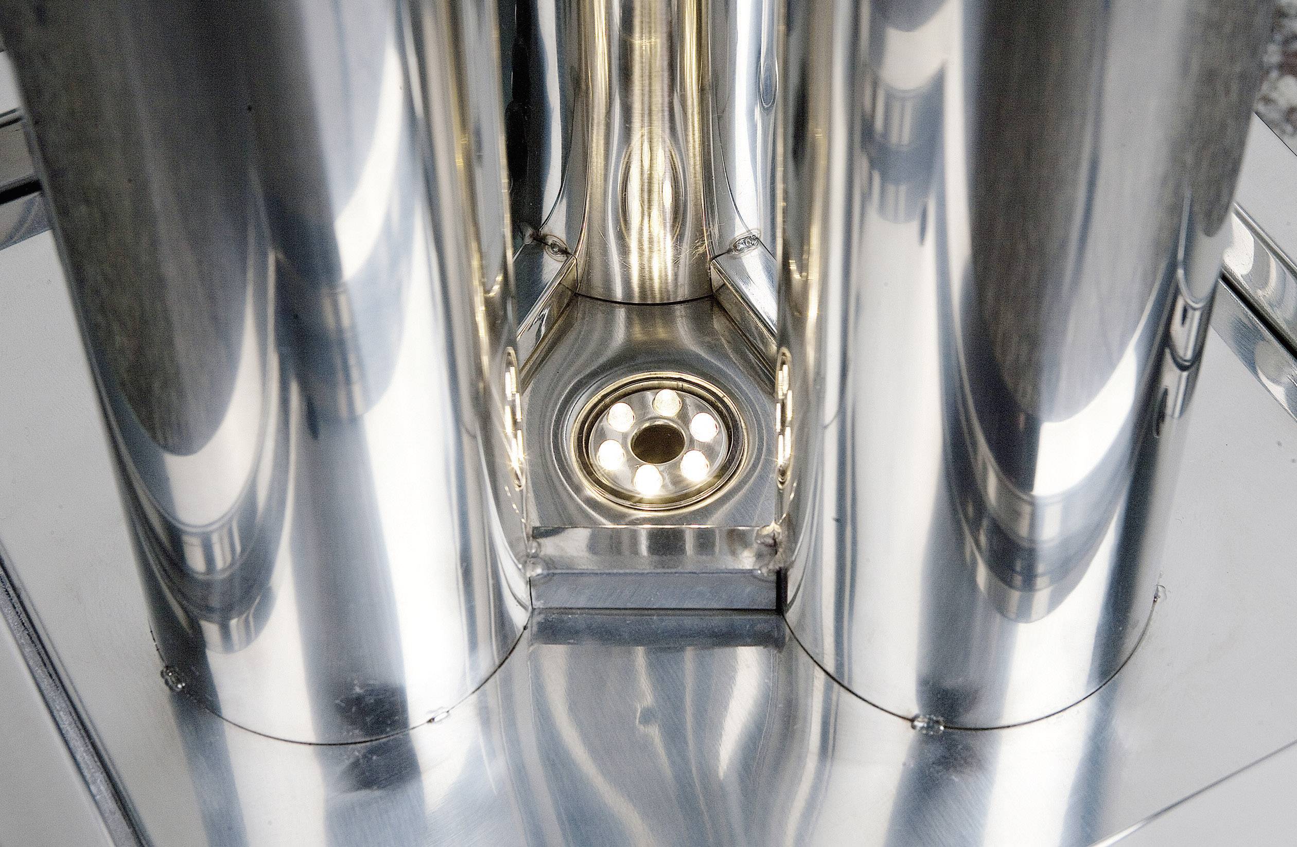 Ein metallisches Kunstwerk mit glänzender Oberfläche und mehreren zylindrischen Formen, die sich zu einer Basis verjüngen.