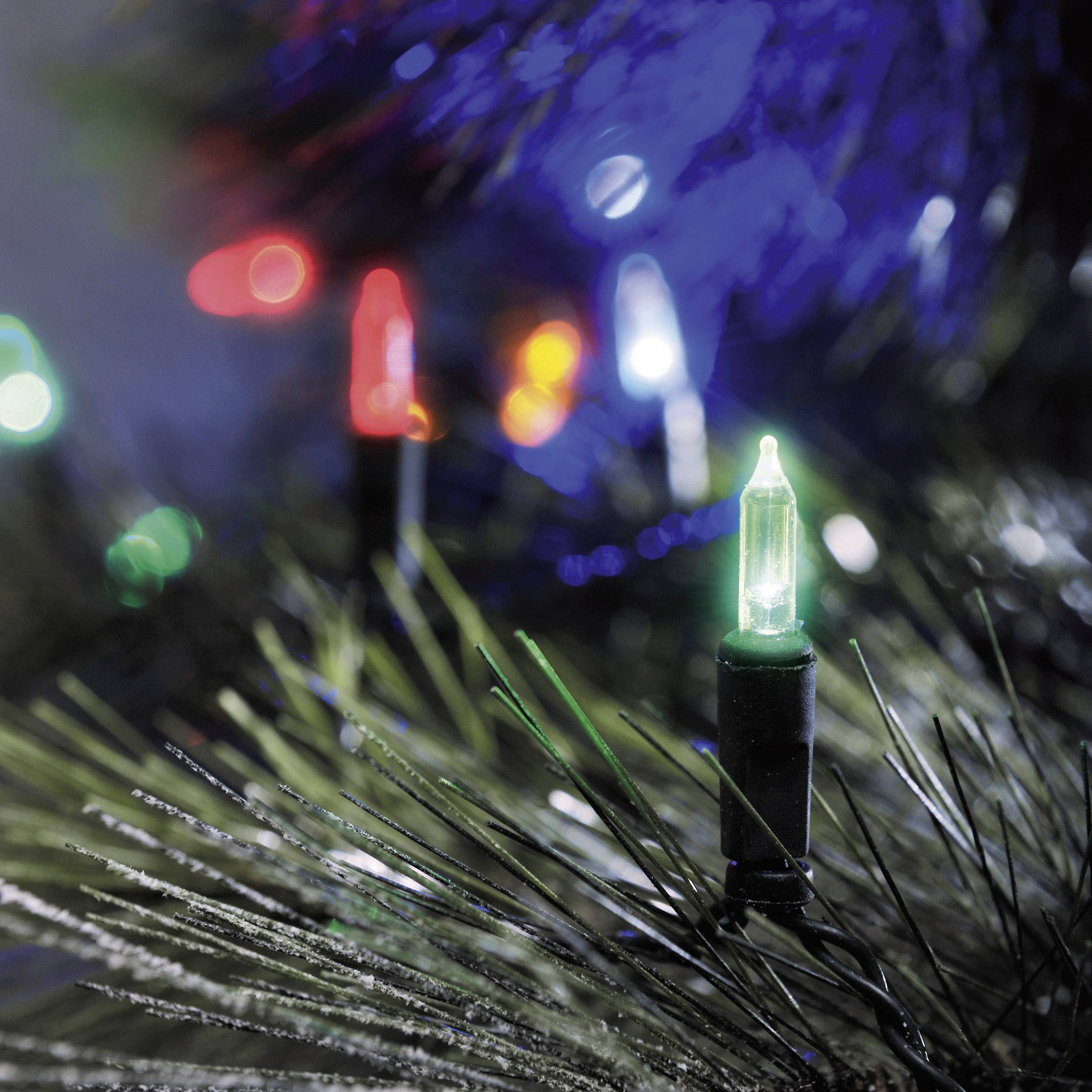Nahaufnahme von bunten Weihnachtslichtern und Tannenzweigen. Grüne, rote und weiße Lichter leuchten zwischen den Nadeln.