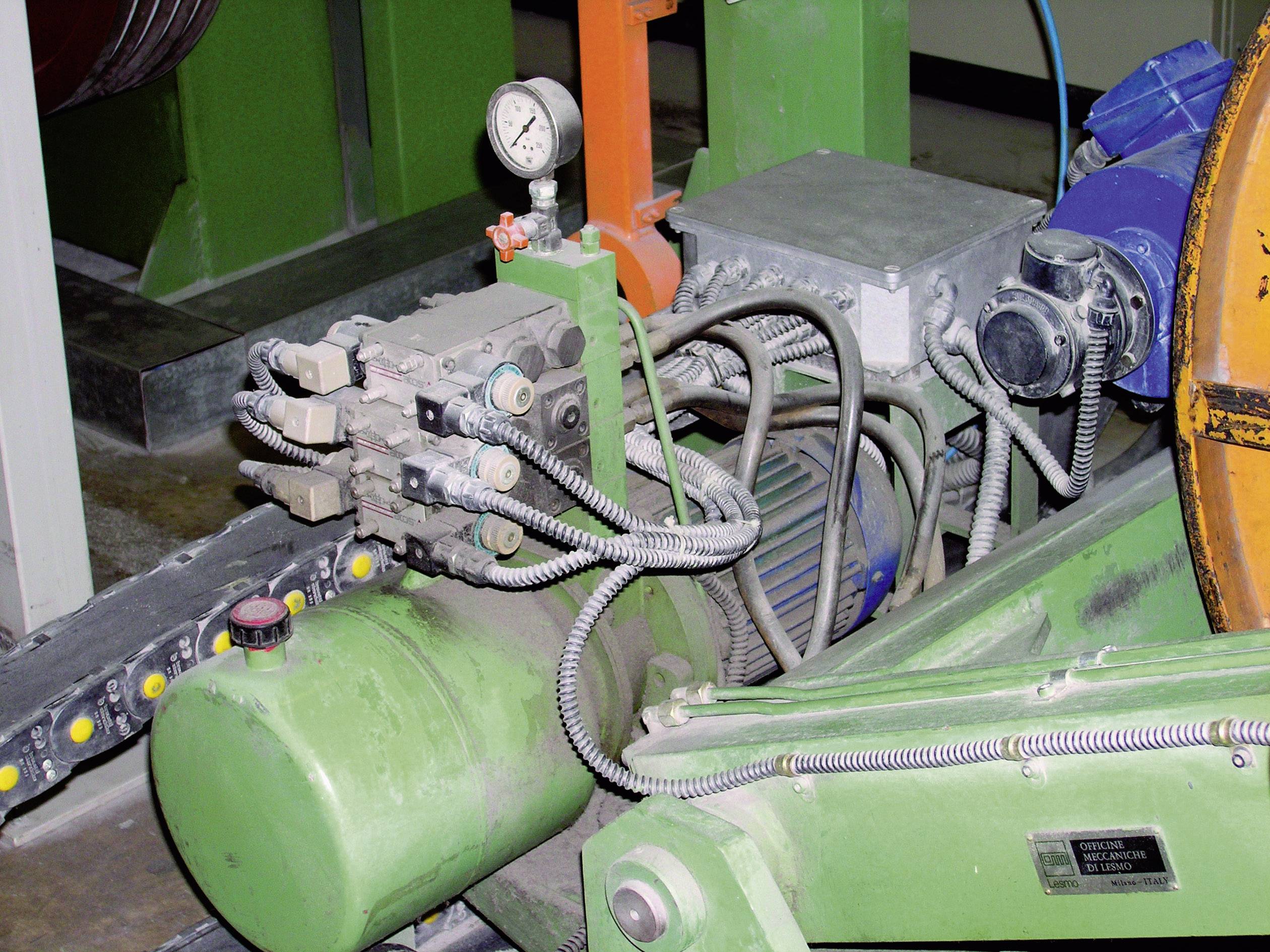 Industrieanlage mit grüner Hydraulikpumpe, mehreren Schläuchen und Manometer.
