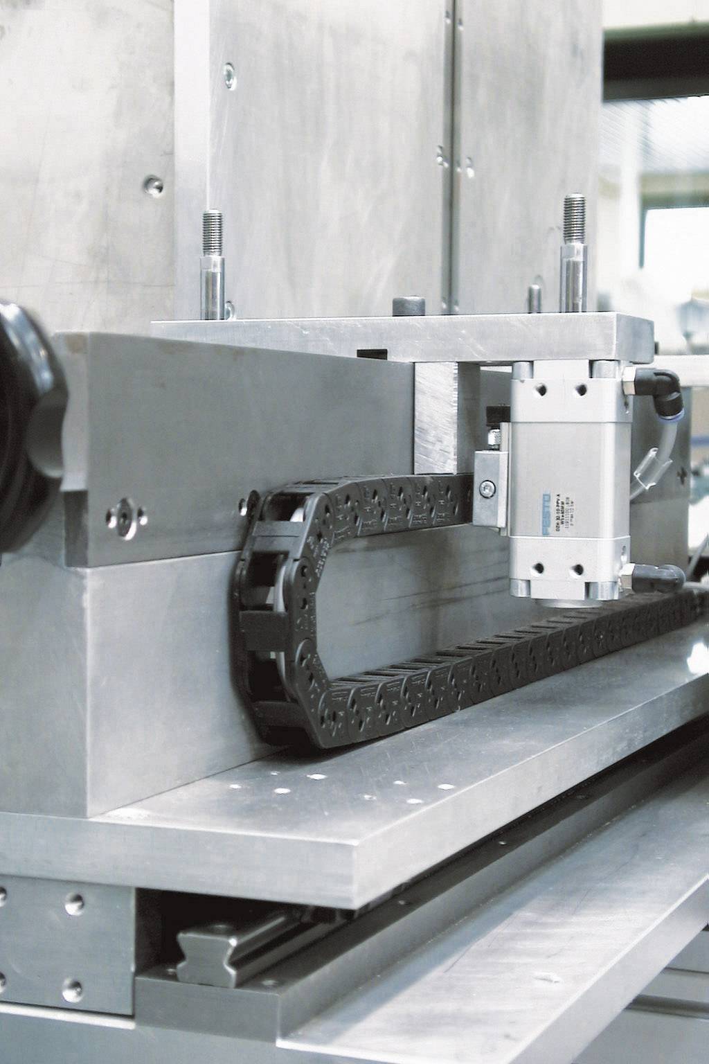 Ein industrieller Fördermechanismus aus Metall mit einer Kette in einer Fabrikumgebung.