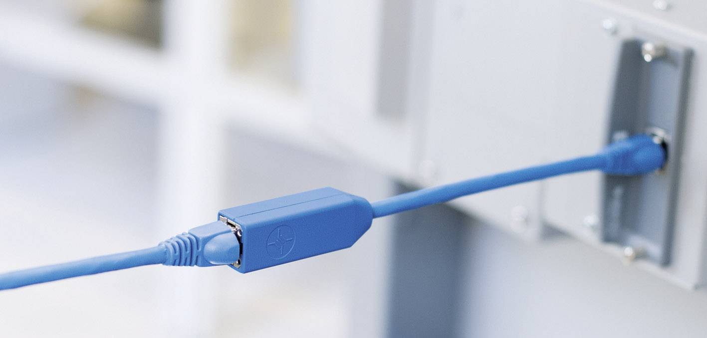Ein blaues Netzwerkkabel ist an ein graues Gerät angeschlossen. Es zeigt eine typische Netzwerkinstallation in einer Büroumgebung.