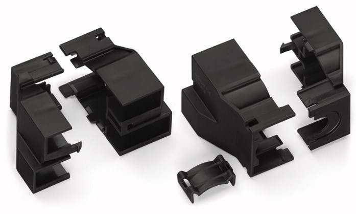 Schwarze Kunststoffteile liegen auf weißem Hintergrund, bestehend aus verschiedenen Formen, möglicherweise Komponenten eines Gehäuses.