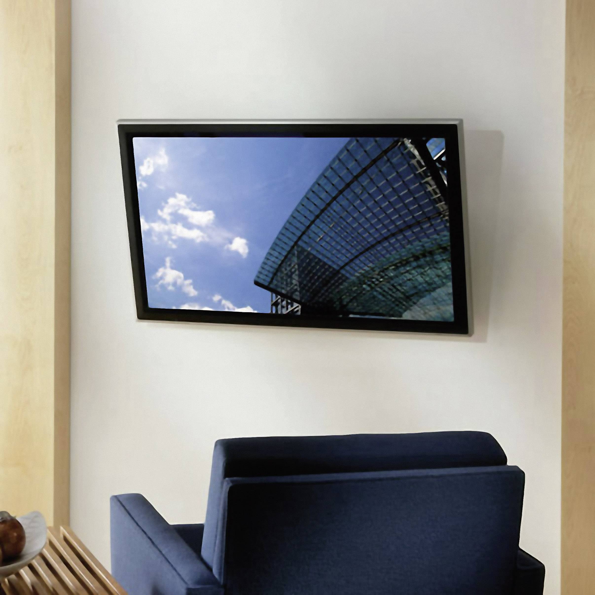 Ein moderner Flachbildfernseher an der Wand zeigt den Himmel und ein Glasgebäude. Im Vordergrund steht ein blauer Sessel.