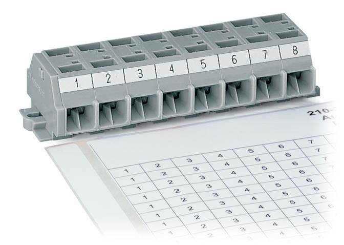 Ein grauer elektrischer Verteilerblock mit acht nummerierten Steckplätzen steht auf einer Tabelle mit Zahlenmatrix im Hintergrund.