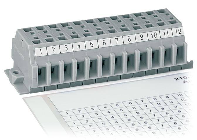 Ein grauer Stromklemmenblock mit nummerierten Anschlüssen von 1 bis 12 liegt auf einem gedruckten Zahlenblatt.