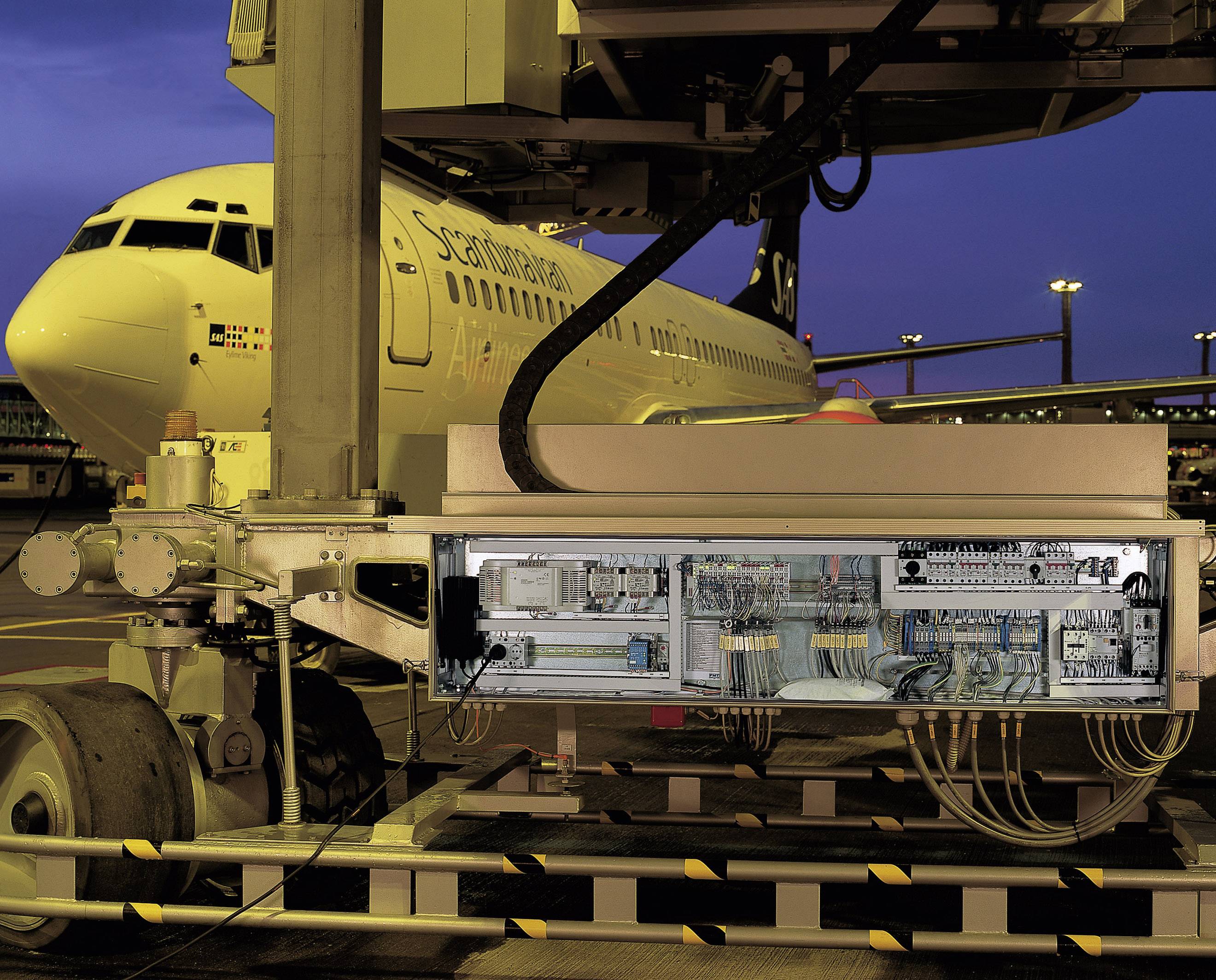 Ein Flugzeug steht auf dem Rollfeld, während ein Servicewagen mit geöffneter Elektronikabdeckung zur Wartung angeschlossen ist.