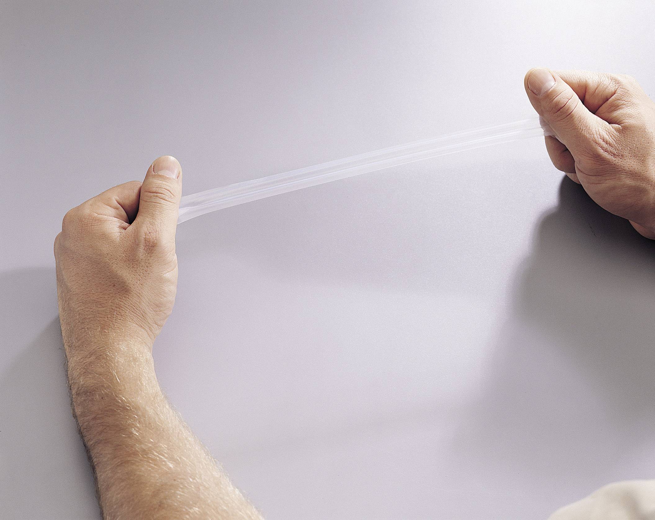 Zwei Hände ziehen an einer durchsichtigen, elastischen Folie. Die Folie ist gespannt, wodurch ihre Dehnbarkeit demonstriert wird.