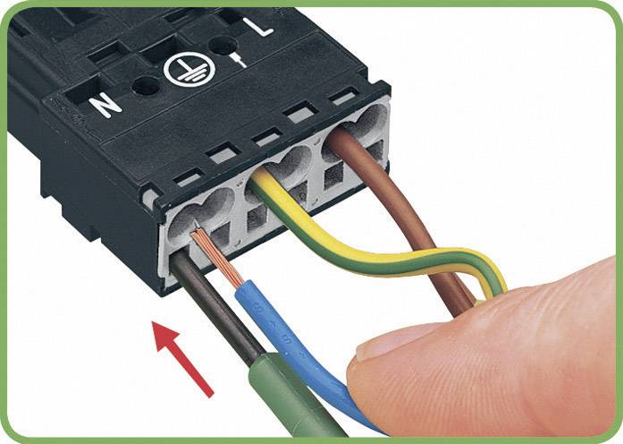 Eine Person zeigt, wie man Drähte in eine elektrische Klemme mit verschiedenen Farbanschlüssen einführt.