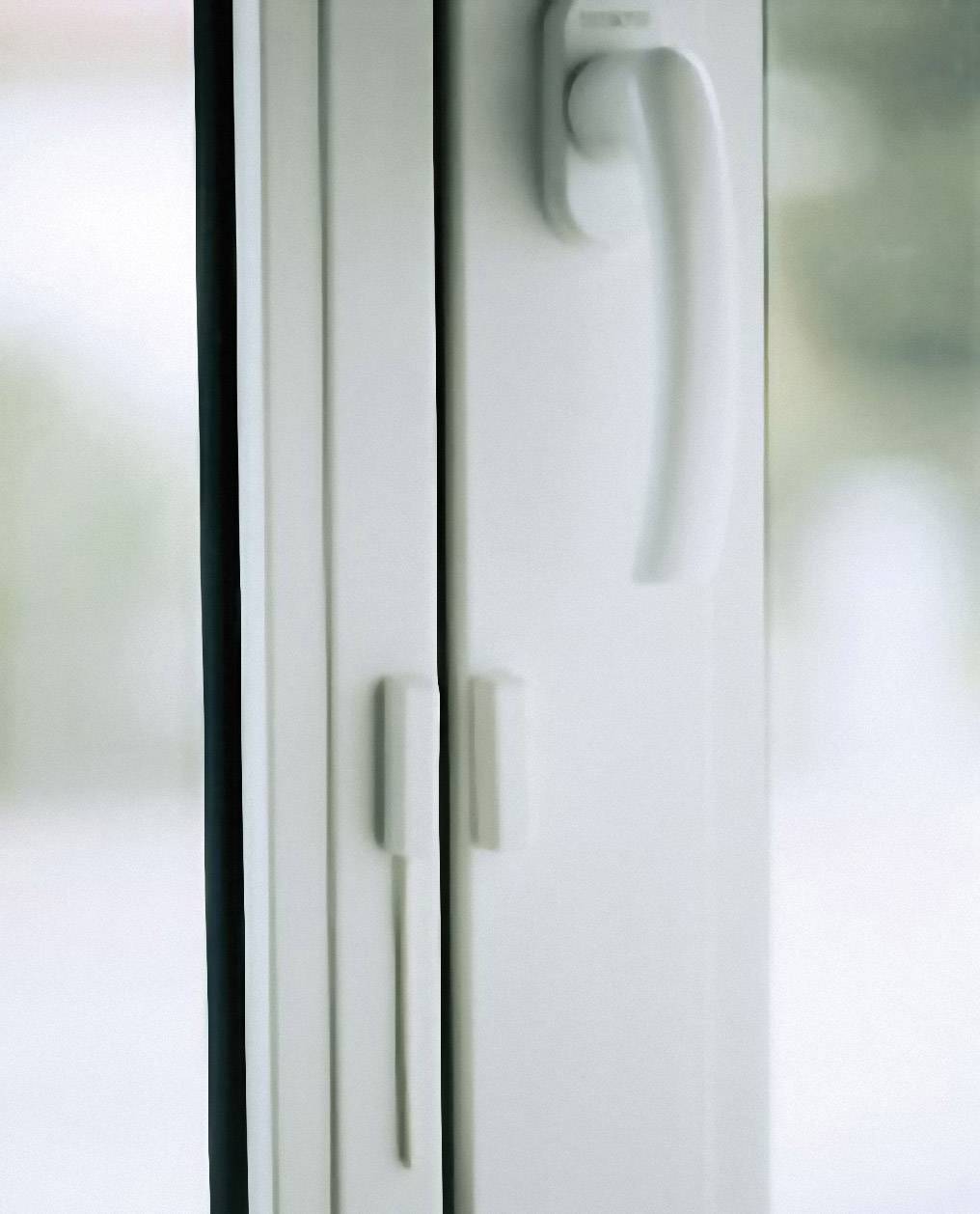 Ein weißer Fenstergriff an einem geschlossenen Glasfenster. Das Bild zeigt ein funktionales Detail zur Bedienung des Fensters.