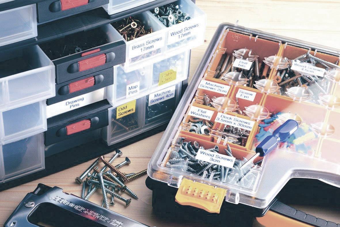 Mehrere Sortierboxen für Werkzeuge und Schrauben, beschriftet mit verschiedenen Typen. Einige Schrauben liegen verstreut davor.