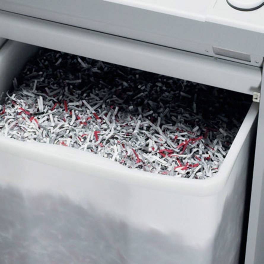 Ein Papierkorb eines Aktenvernichters ist mit kleinen Papierstreifen gefüllt.