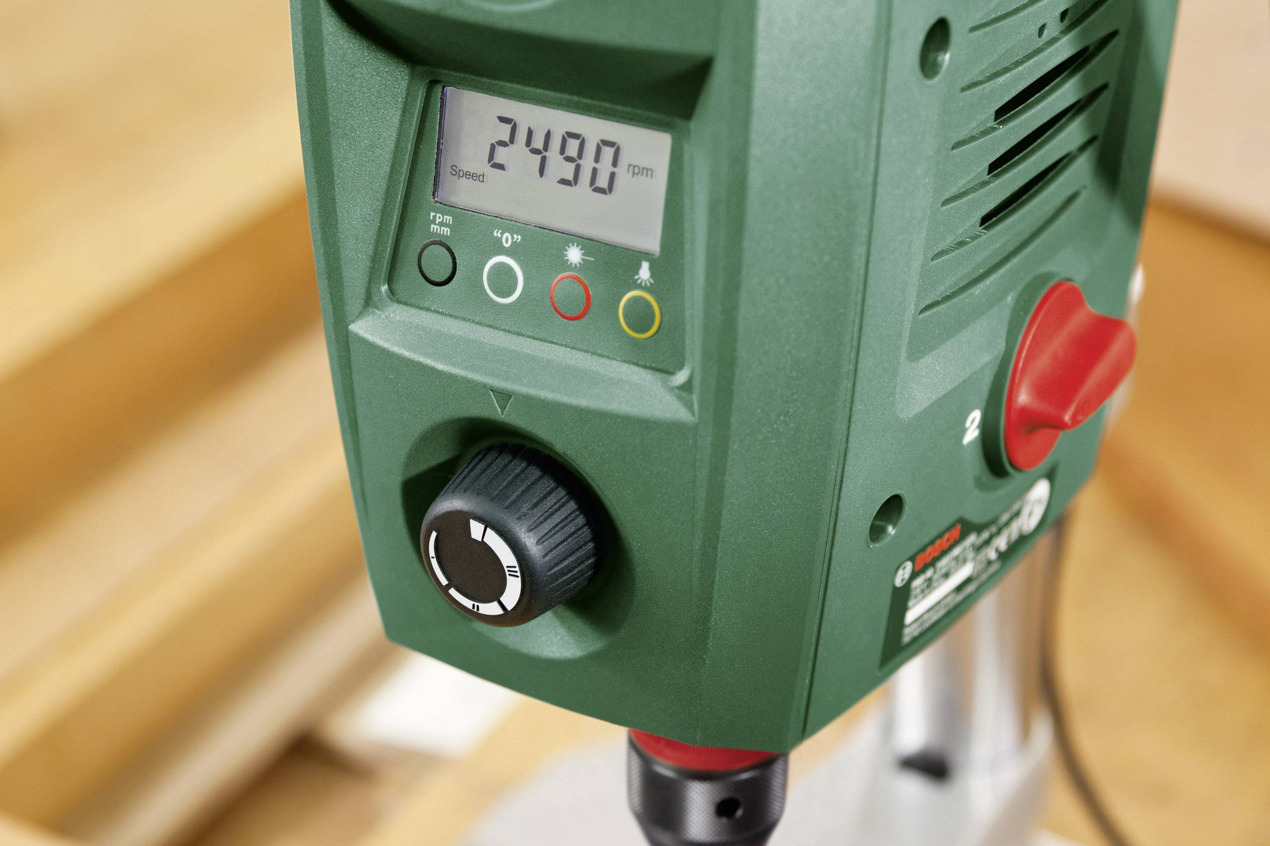 Grüne Tischbohrmaschine im Nahaufnahme. Das digitale Display zeigt die Drehzahl '2490 rpm'. Links Drehregler und Statusanzeigen.