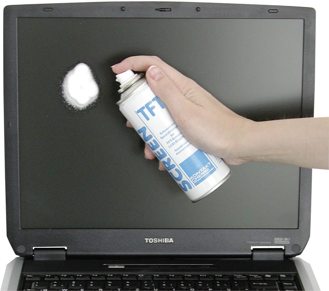 Eine Hand sprüht Reiniger auf einen Laptop-Bildschirm. Der Bildschirm zeigt einen weißen Schaumfleck von der Sprühflasche.