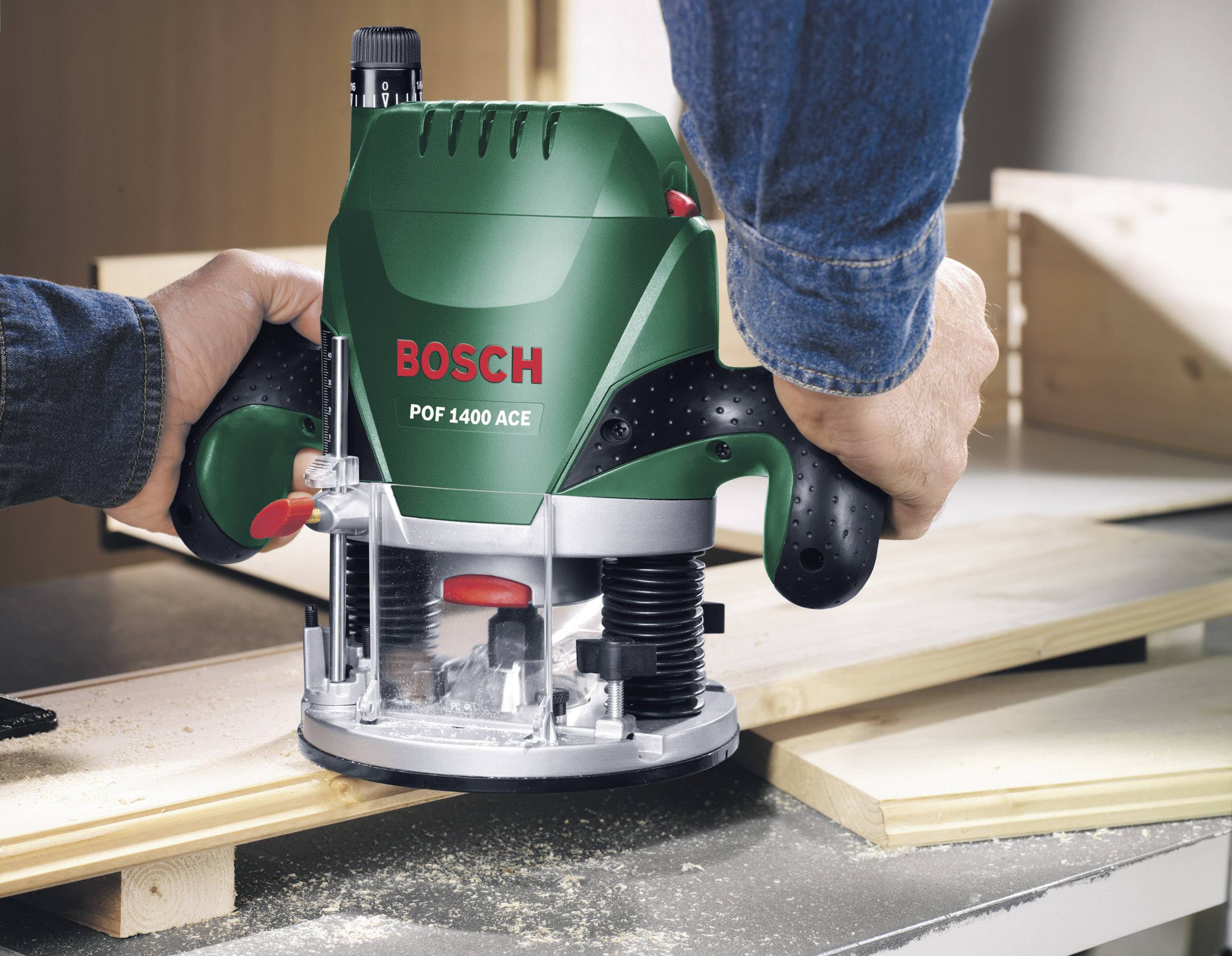 Eine Person arbeitet mit einer grünen Oberfräse, graviert Holz auf einer Werkbank.