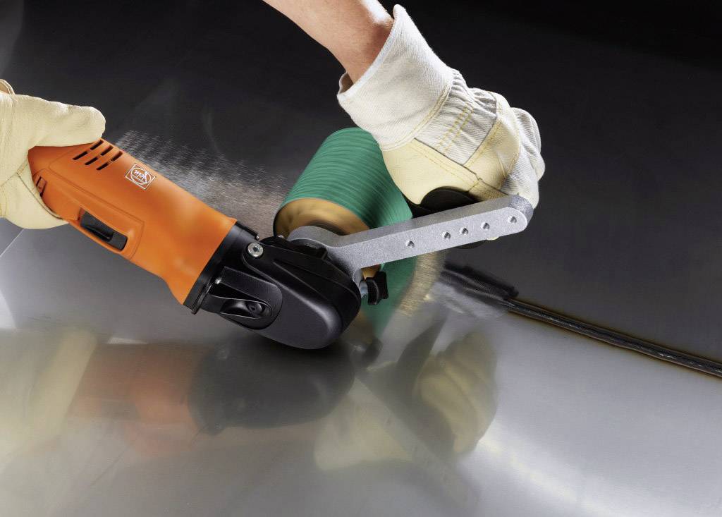 Eine Person verwendet ein rotierendes Elektrowerkzeug mit einem grünen Aufsatz, um eine Metalloberfläche zu polieren.