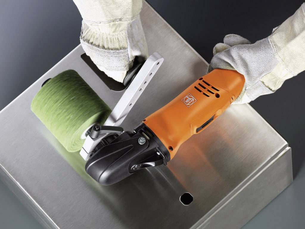 Person trägt Handschuhe und benutzt ein orangefarbenes Elektrowerkzeug mit Schleifaufsatz, um eine Metalloberfläche zu polieren.