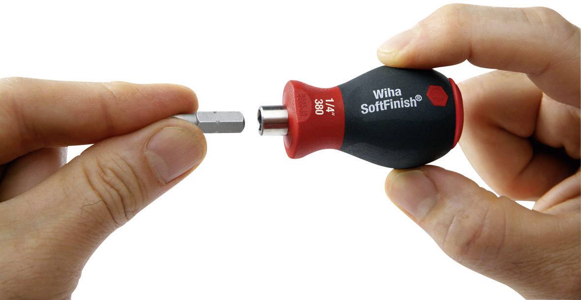 Eine Hand hält einen Schraubendrehergriff, während die andere Hand einen Bit einsetzt. Der Griff trägt die Aufschrift 'Wiha SoftFinish'.