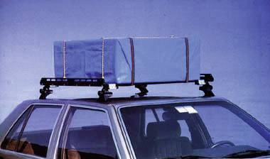 Ein Auto mit einem blauen Gepäckträger auf dem Dach, der mit Gurten gesichert ist. Das Fahrzeug steht vor einem blauen Hintergrund.