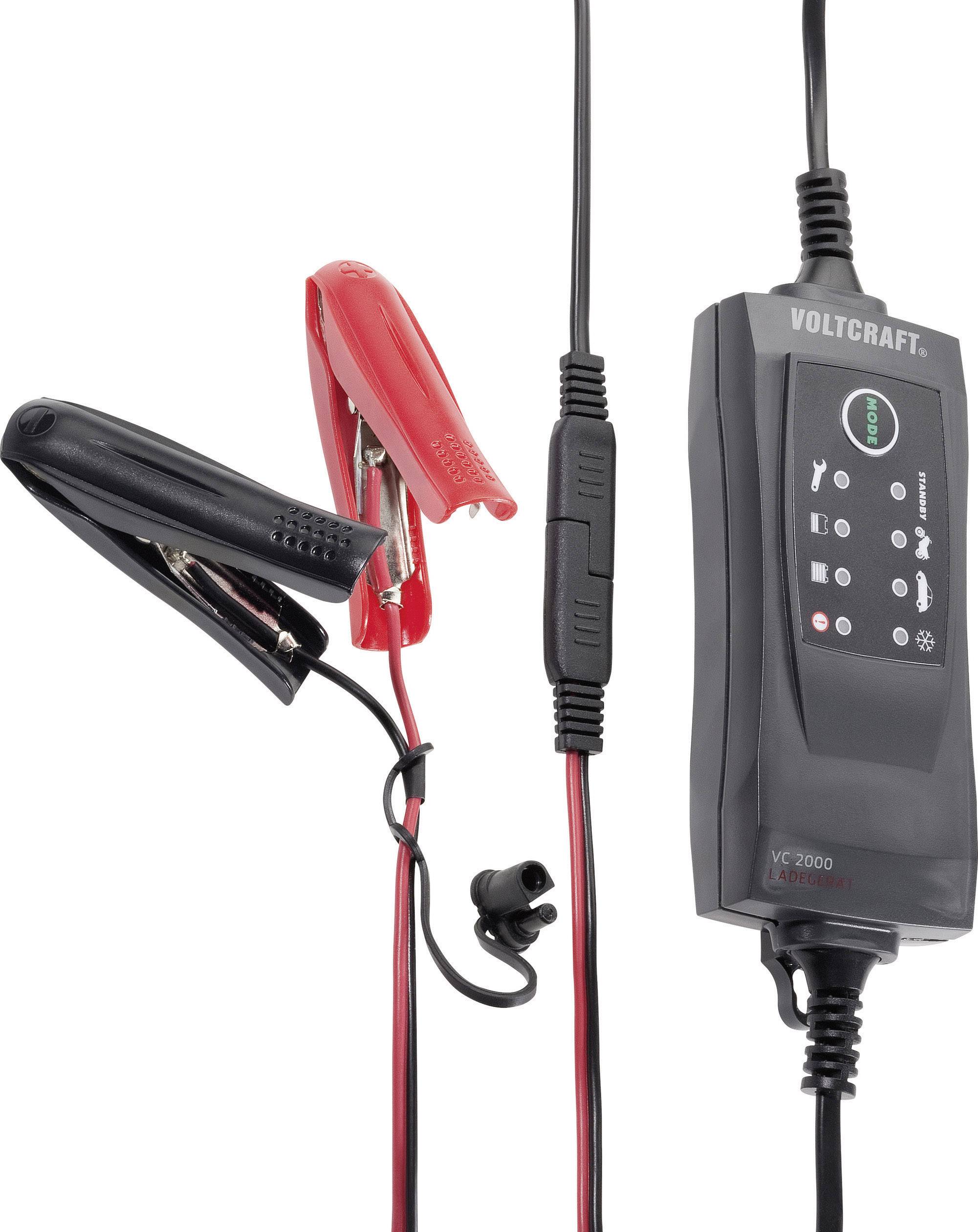 Ladegerät mit zwei Klemmen, eine rot und eine schwarz, für Autobatterie. Gerät zeigt Ladefortschritt mit verschiedenen Symbolen an.