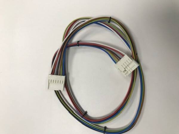 Mehrfarbiges Kabel mit zwei weißen Steckverbindern an den Enden, auf einer weißen Oberfläche liegend.