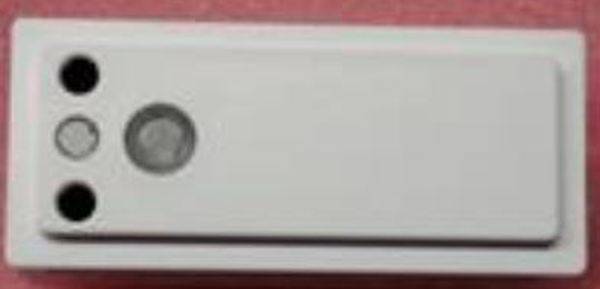 Weiße rechteckige Taste mit runden, erhabenen Elementen, die zur Bedienung einer elektronischen Vorrichtung verwendet wird.