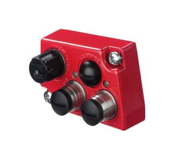 Rotes Steuerpult mit zwei silbernen Tasten, einem schwarzen Knopf und einem schwarzen Schalter.