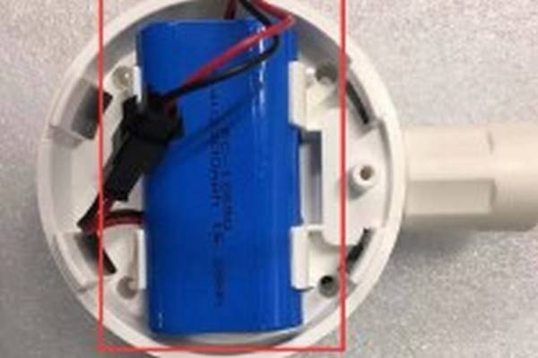 Batterie in einer runden weißen Halterung mit Kabeln, die an elektrische Komponenten angeschlossen sind.