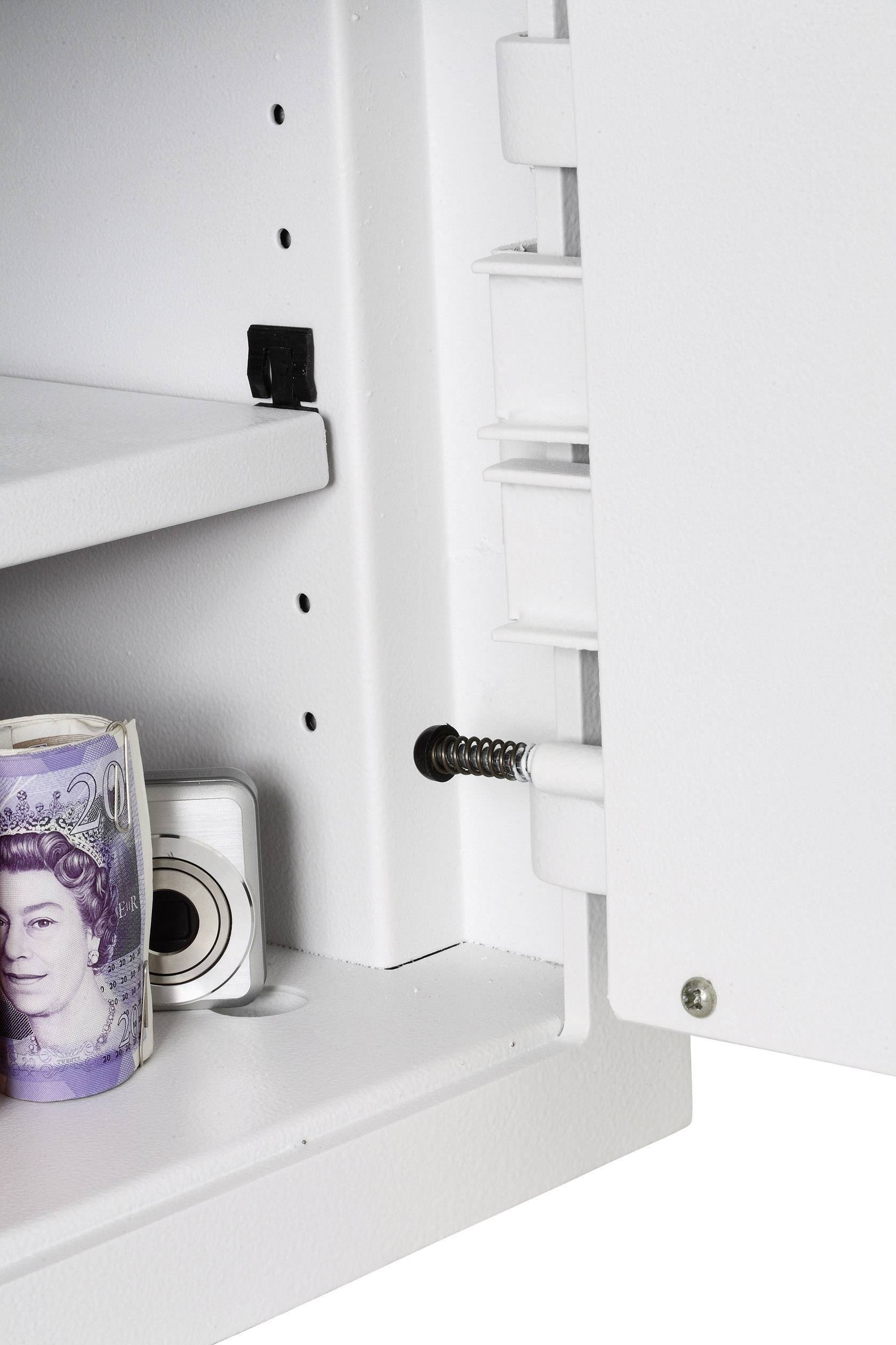 Ein geöffneter Safe zeigt eine zusammengerollte britische Banknote mit dem Porträt einer Frau und eine kleine Digitalkamera im Inneren.
